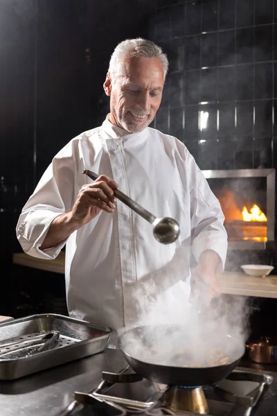 Chef joyeux cuisine champignons sur la poêle — Photo