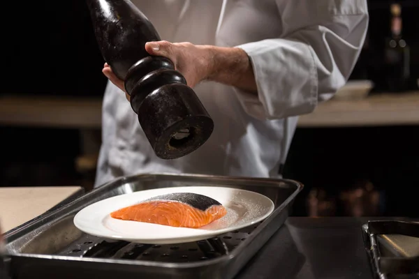 Concentrated chef putting salt on the salmon steak — Stock Photo, Image