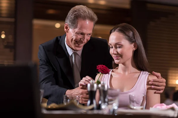 Lächelnder positiver Mann, der der Frau eine Rose schenkt — Stockfoto