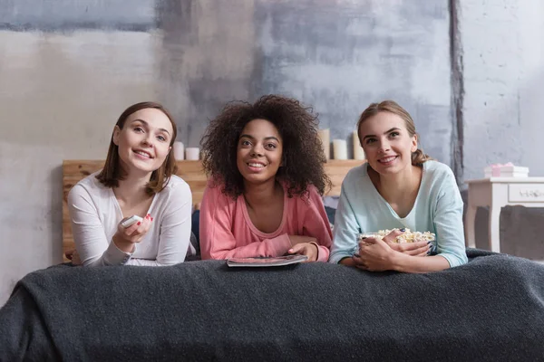 Chicas sonrientes tumbadas en la cama en casa —  Fotos de Stock