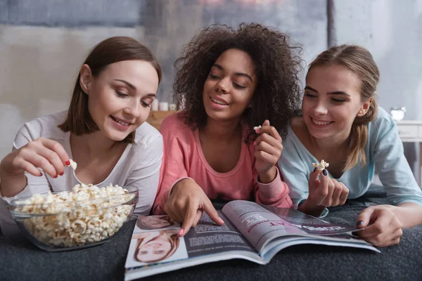 Sorrindo amigos envolvidos olhando para a revista — Fotografia de Stock