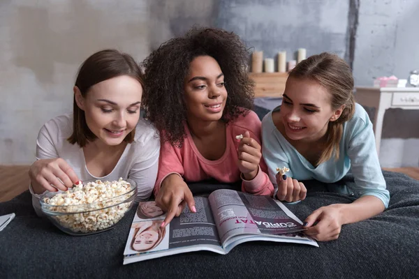 Divertido envolvido meninas lendo a revista em casa — Fotografia de Stock