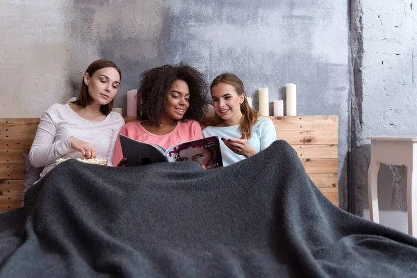 Encantadas chicas sonrientes leyendo la revista en la cama — Foto de Stock