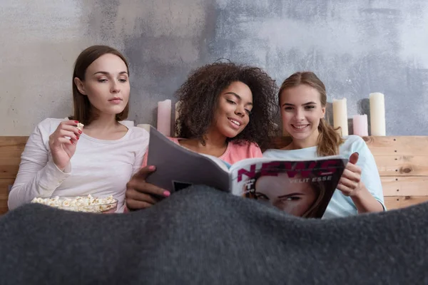 Meninas bonitas alegres discutindo a revista na cama — Fotografia de Stock