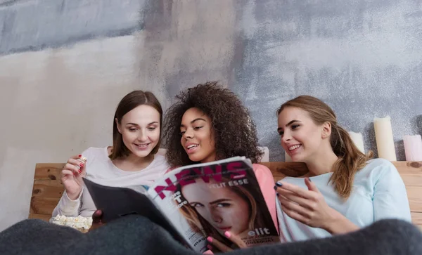 Amigos envolvidos lendo e discutindo a revista em casa — Fotografia de Stock
