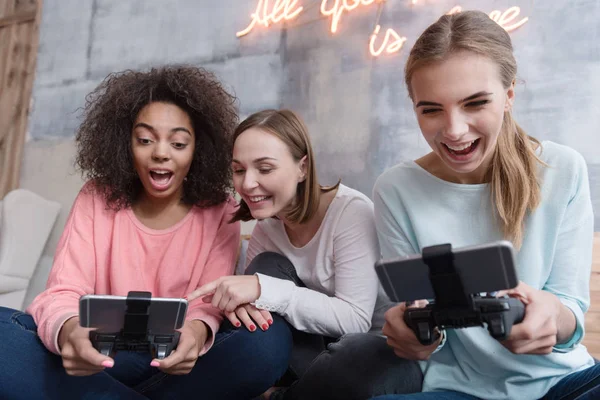 Meninas divertidas segurando consolas de jogos e jogando jogos — Fotografia de Stock