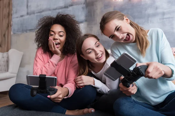 Rindo meninas segurando consoles de jogos e jogando jogos — Fotografia de Stock