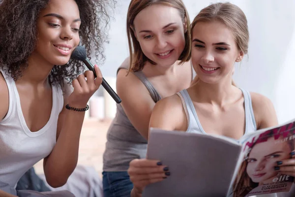 Delighted smiling girls reading the magazine at home — Stock Photo, Image