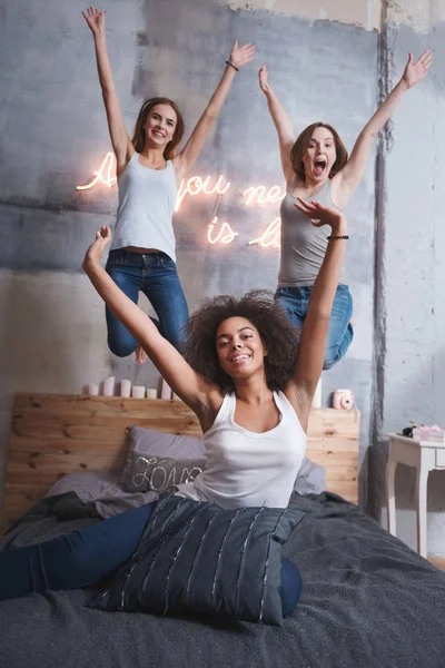 Lachende Freunde, die auf dem Bett springen und Spaß haben — Stockfoto