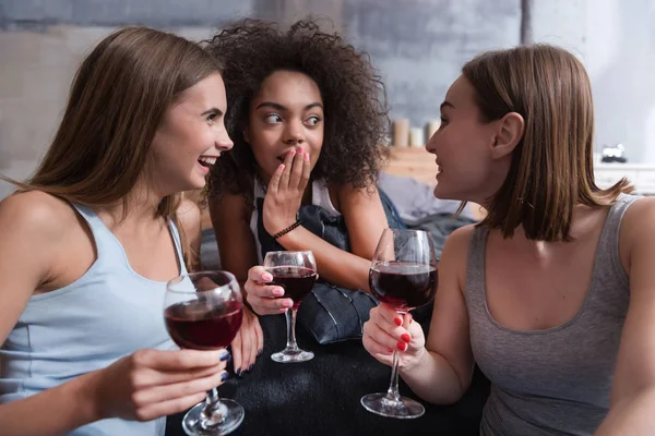 Geamuseerd meisjes drinken van wijn en roddelen — Stockfoto