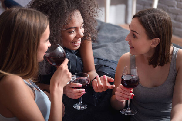 Забавные девушки пьют вино и ведут захватывающие беседы
