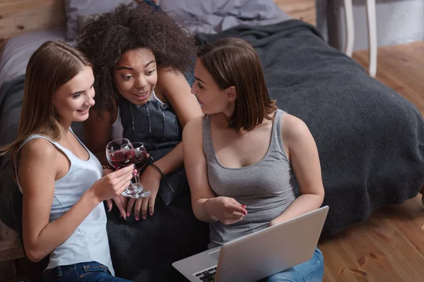 Amigos involucrados bebiendo vino y mirando en el portátil — Foto de Stock