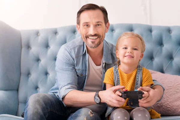 Padre cariñoso positivo enseñando a su hija a jugar videojuegos —  Fotos de Stock