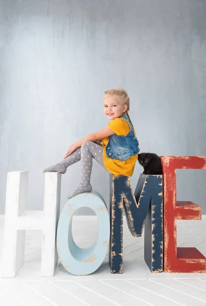 Gelukkig positieve meisje zittend op de grote houten letters — Stockfoto