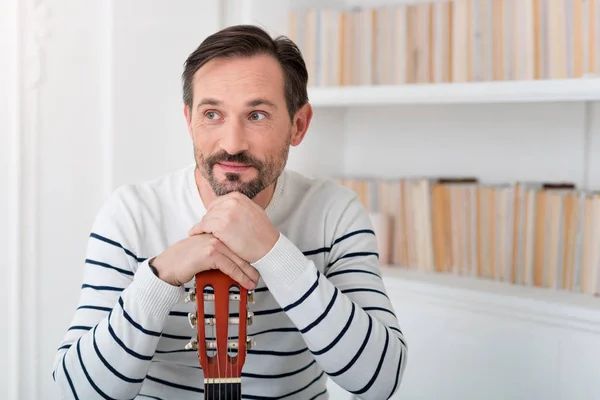 Optimistic dreamy man leaning on the guitar — Stock Photo, Image