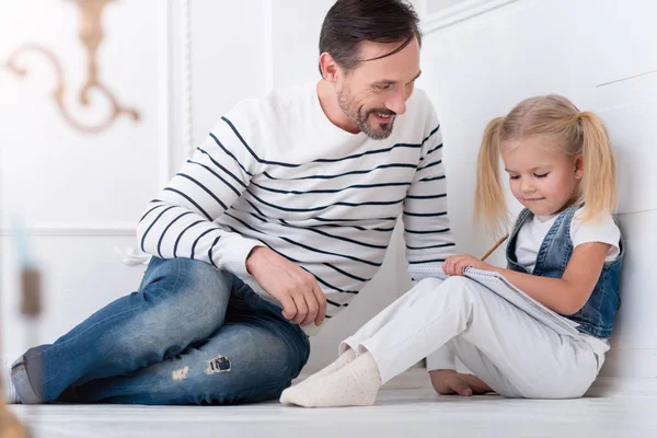 Веселый заботливый отец помогает своей дочери с домашним заданием — стоковое фото