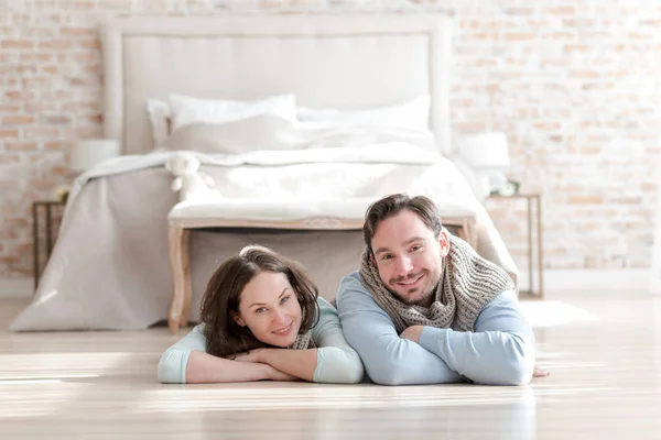 Feliz pareja positiva acostada frente a la cama — Foto de Stock