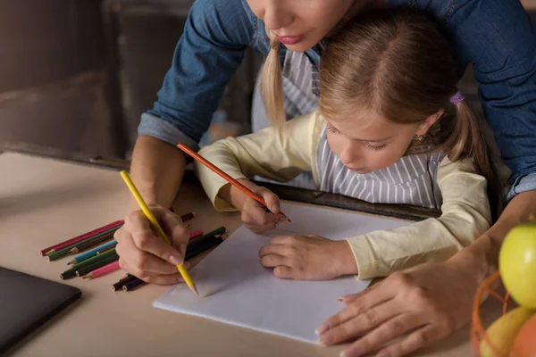 Härlig liten flicka ritar med mamman i köket — Stockfoto