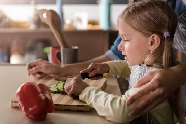 Niña concentrada cortando un pepino con su madre —  Fotos de Stock