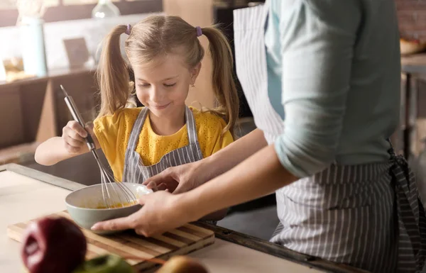 Lächelndes Mädchen, das mit seiner Mutter Eier in der Schüssel mixt — Stockfoto