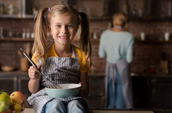 Χαμογελαστό κοριτσάκι ανάμειξη τα αυγά στην κουζίνα — Φωτογραφία Αρχείου