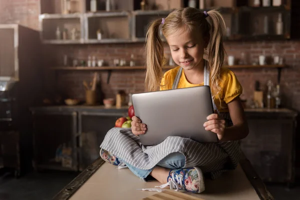 保持しているタブレットを見て面白がっての快適な女の子 — ストック写真