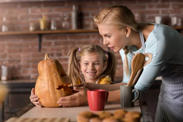 Delighted girl touching a pumpkin with her mother — Stock Photo, Image