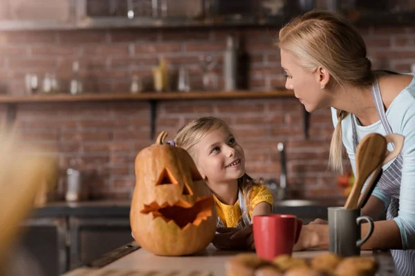 Smiling girl preparing a pumpkin for Halloween with her mother — Stock Photo, Image