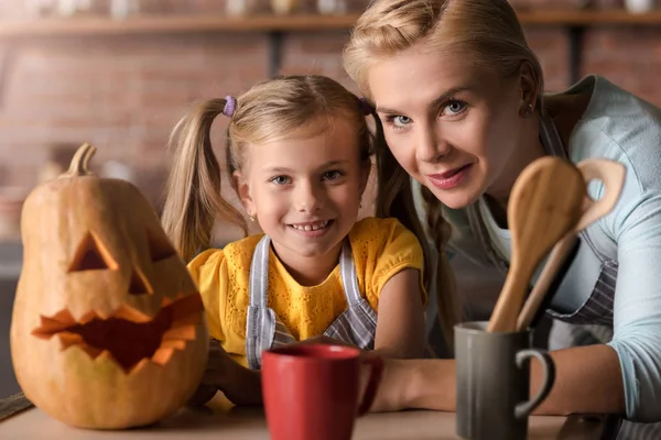 Happy girl sitting near the pumpkin with her mother — Stock Photo, Image