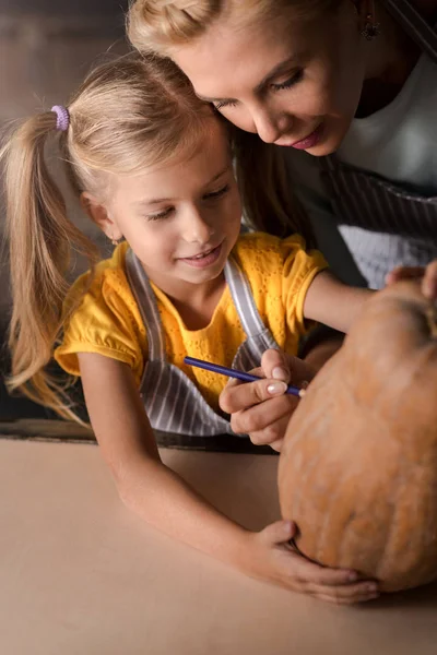 Delighted girl preparing a pumpkin for Halloween with her mother — Stock Photo, Image