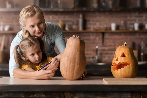Delighted girl preparing a pumpkin for Halloween with her mother — Stock Photo, Image