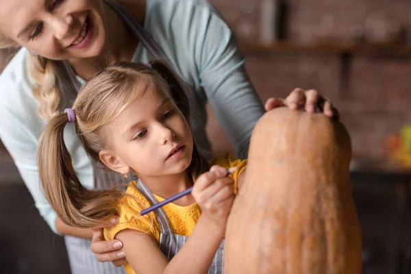 Concentrated girl preparing jack o lantern with her mother — Stock Photo, Image