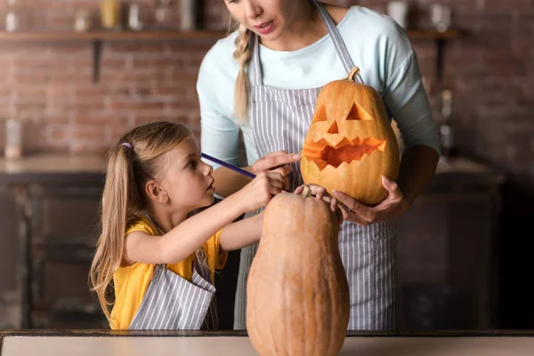 Involved girl preparing jack o lantern with her mother — Stock Photo, Image