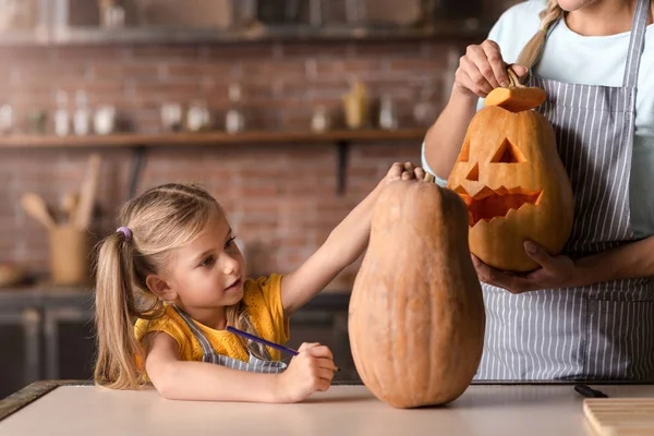 Delighted girl preparing jack o lantern with her mother — Stock Photo, Image