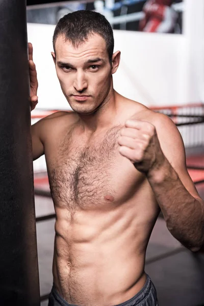 Handsome man standing near punching bag — Stock Photo, Image