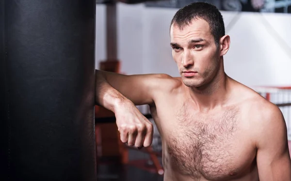 Jóképű férfi támaszkodva boxzsák — Stock Fotó