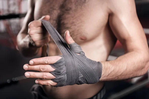 Gros plan de l'homme enveloppant la main dans du ruban de boxe — Photo