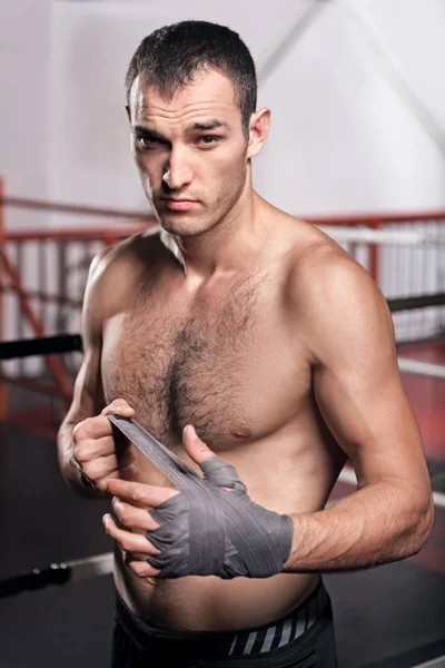 Handsome man wrapping hand in boxing bandage — Stock Photo, Image