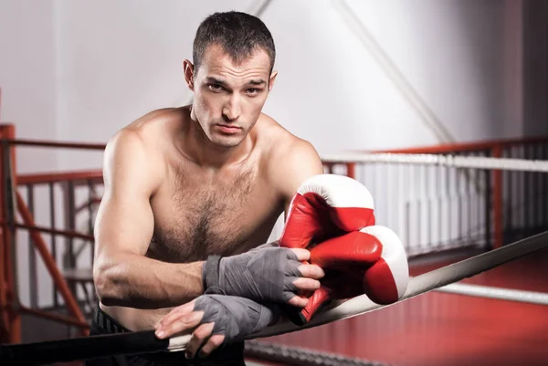 Man leaning on ring rope while holding boxing gloves — Stock Photo, Image