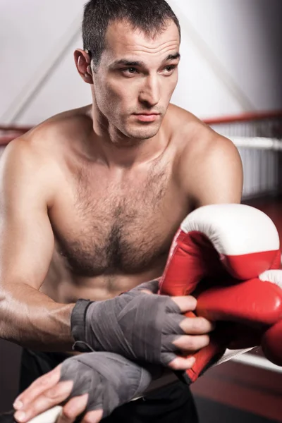 Man leaning on ring rope while holding boxing gloves — Stock Photo, Image