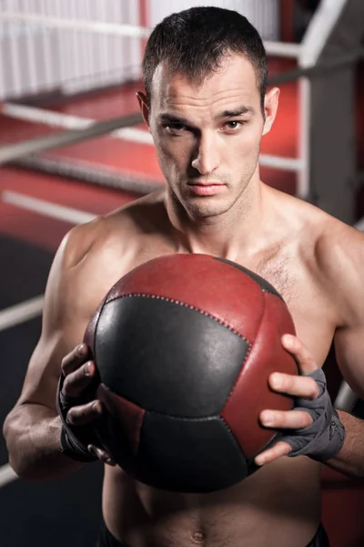 Hombre muscular sosteniendo la pelota de fitness delante del pecho — Foto de Stock