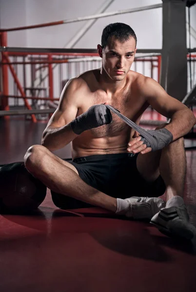 Спортсмен обмотує руки в боксерській пов'язці на підлозі — стокове фото