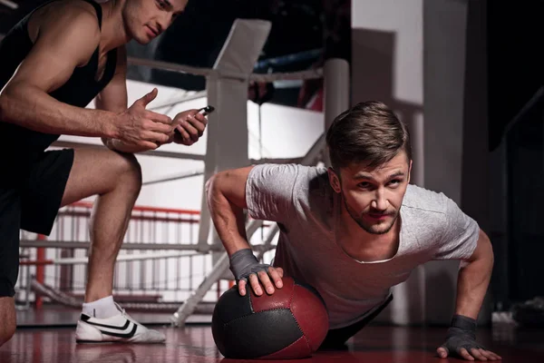 Mann macht Liegestütze mit Trainer mit Fitnessball — Stockfoto