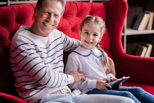 Chica descansando con su abuelo y sosteniendo la consola de juegos —  Fotos de Stock