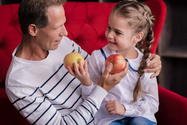 Uśmiechnięta dziewczynka gospodarstwa dwa jabłka z jej dziadek — Zdjęcie stockowe