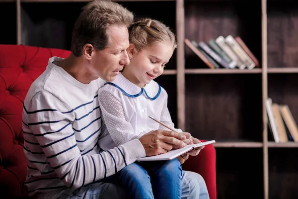 Ragazzina che scrive con suo nonno — Foto Stock