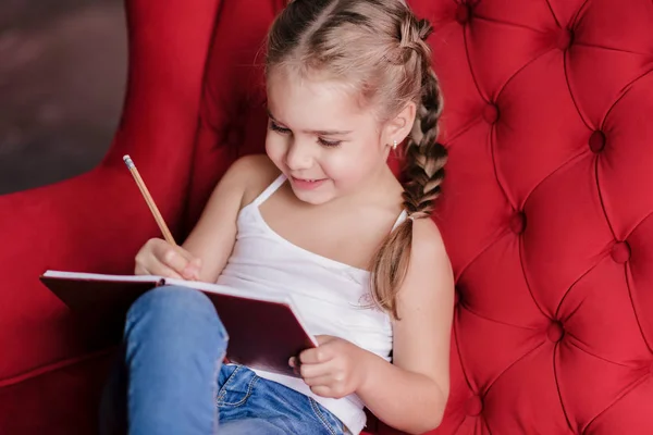 Маленькая улыбающаяся девочка рисует — стоковое фото