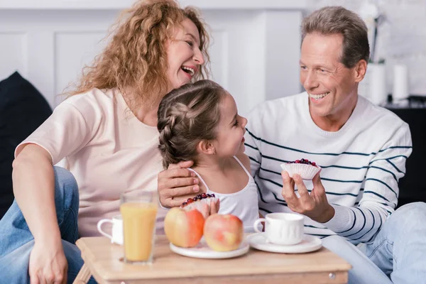 Laughing girl holding berry cupcakes met haar grootouders — Stockfoto