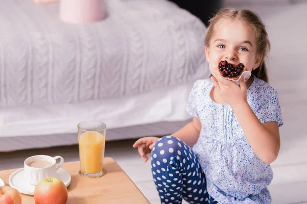 Aranyos kis lány ül a földön, és eszik cupcake — Stock Fotó