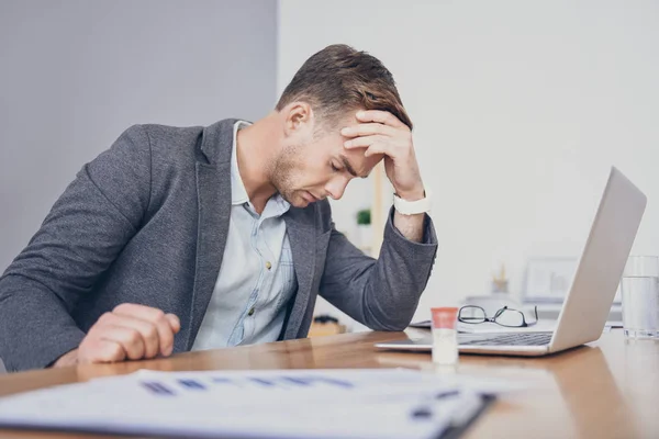 Tired young man using laptop and having headache. — Stock Photo, Image